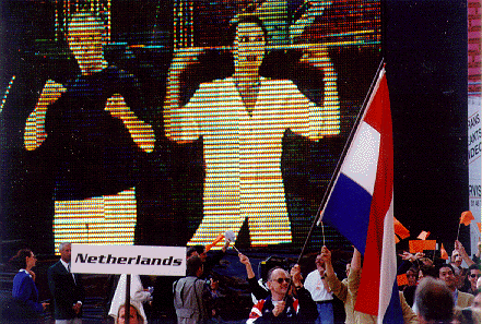 De tolken gebarentaal geven op een groot scherm aan:'de Nederlandse equipe betreedt het stadion'.